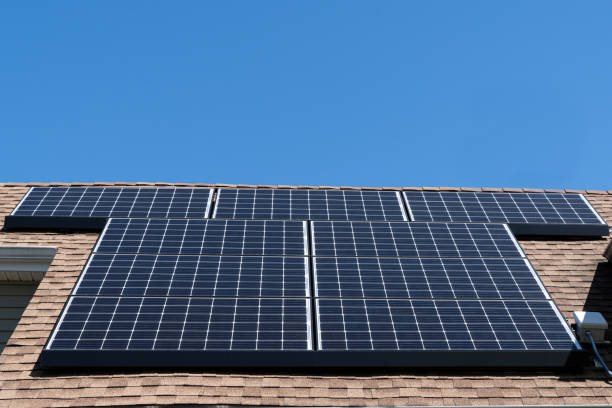 Residential solar array mounted on an asphalt shingle roof under a blue sky